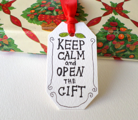 Handmade hang tag with a red hanging satin ribbon and a writing Keep calm and open the gift with hand-drawn details around