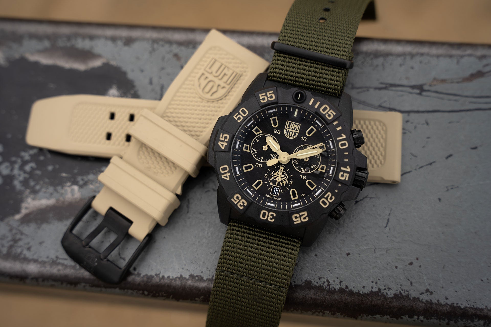 The watch has two interchangeable straps; a sand-coloured rubber strap and an olive webbing strap.