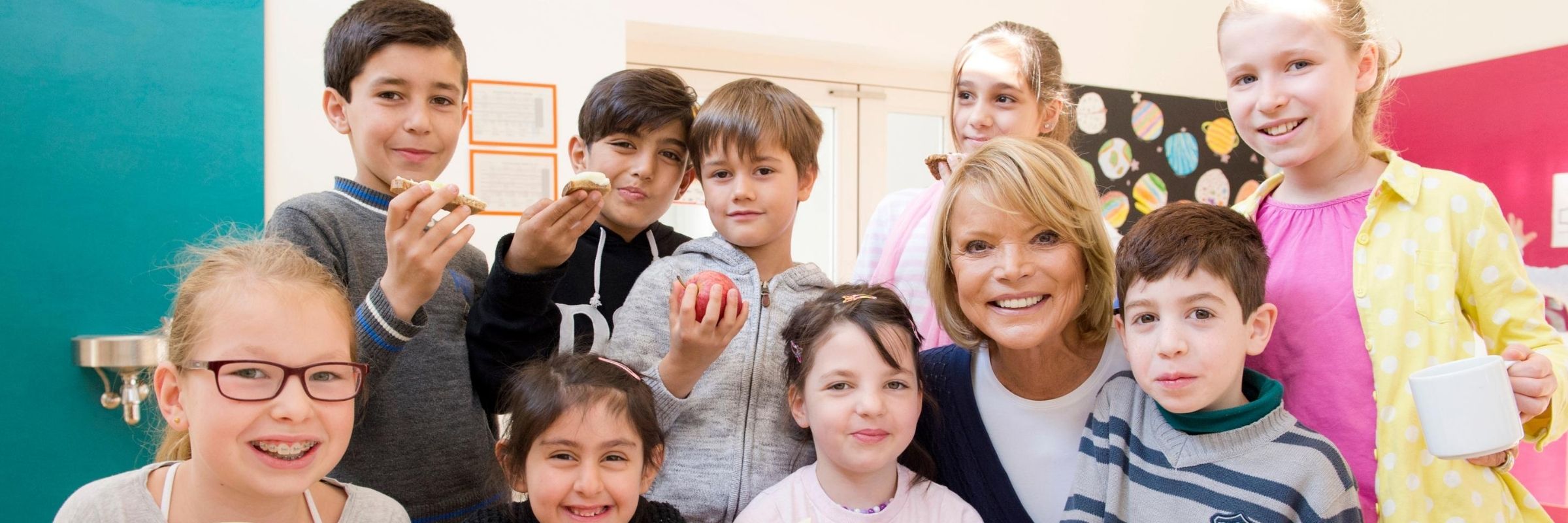 Uschi Glas lächelt mit neun glücklichen Kindern in die Kamera 