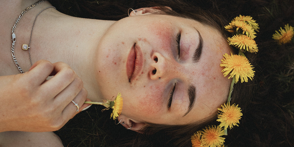 Young woman with a dandelion flower crown lying on her back with a relaxed expression on her face