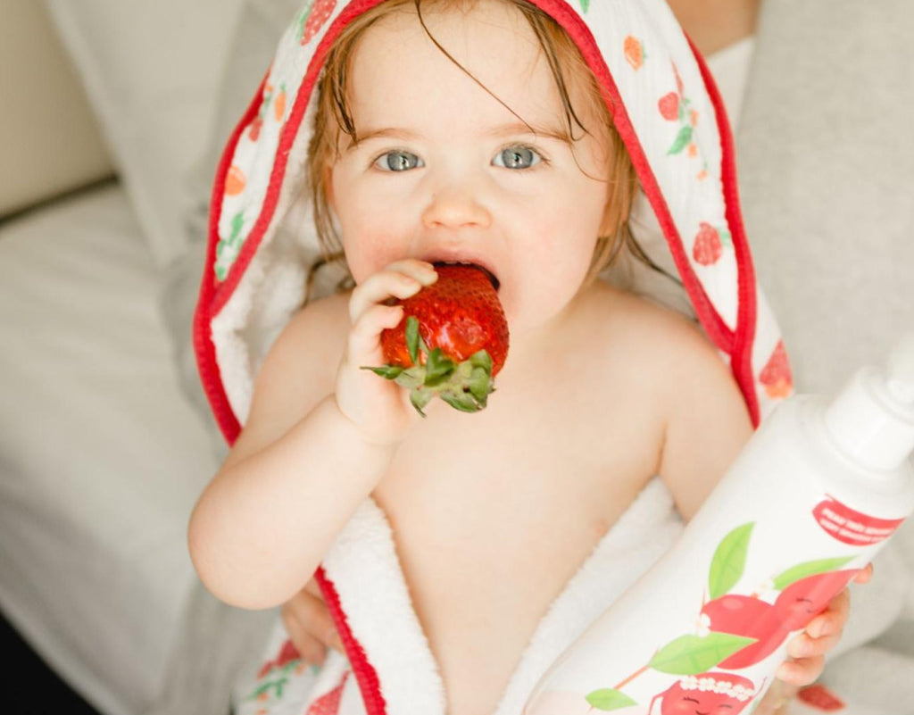 baby eating a strawberry on 12 month old feeding schedule