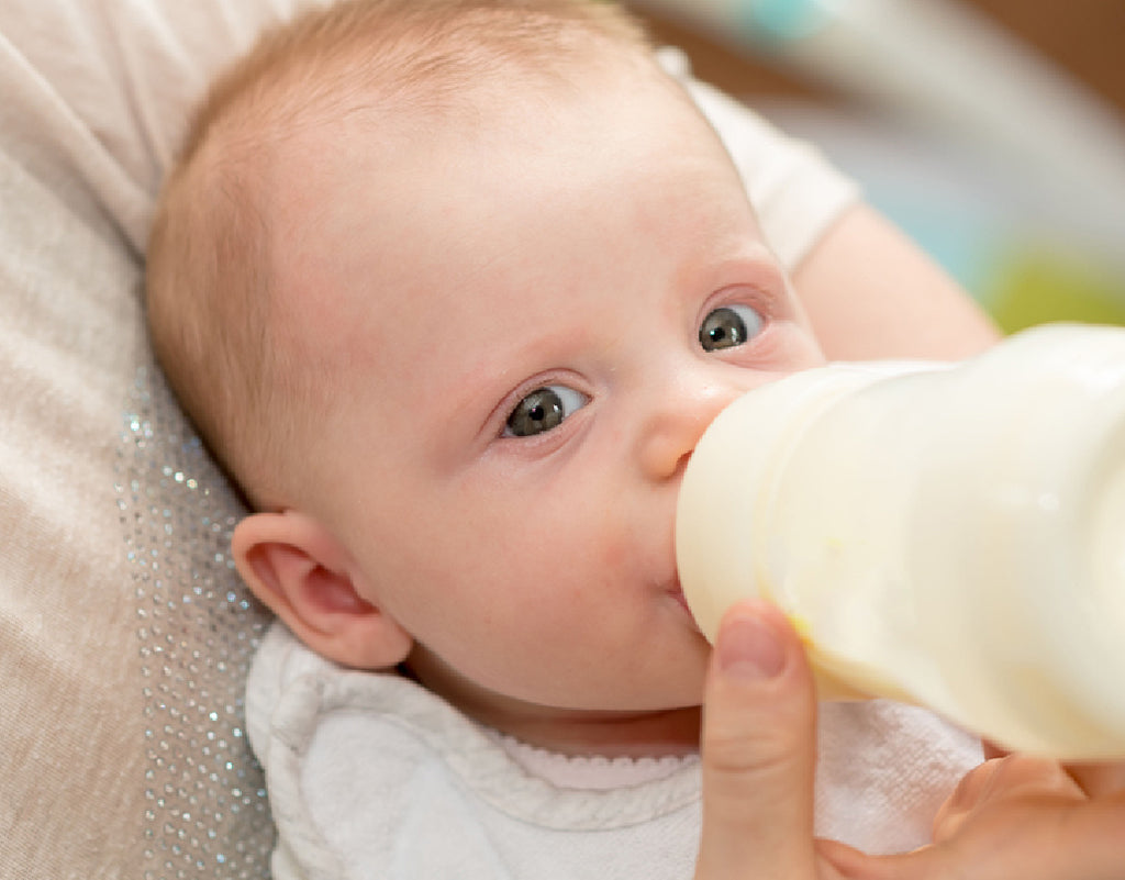 Baby drinking a bottle on a 3 month old feeding schedule