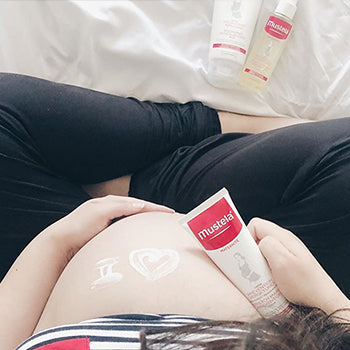 6-months-pregnant women applying stretch marks cream