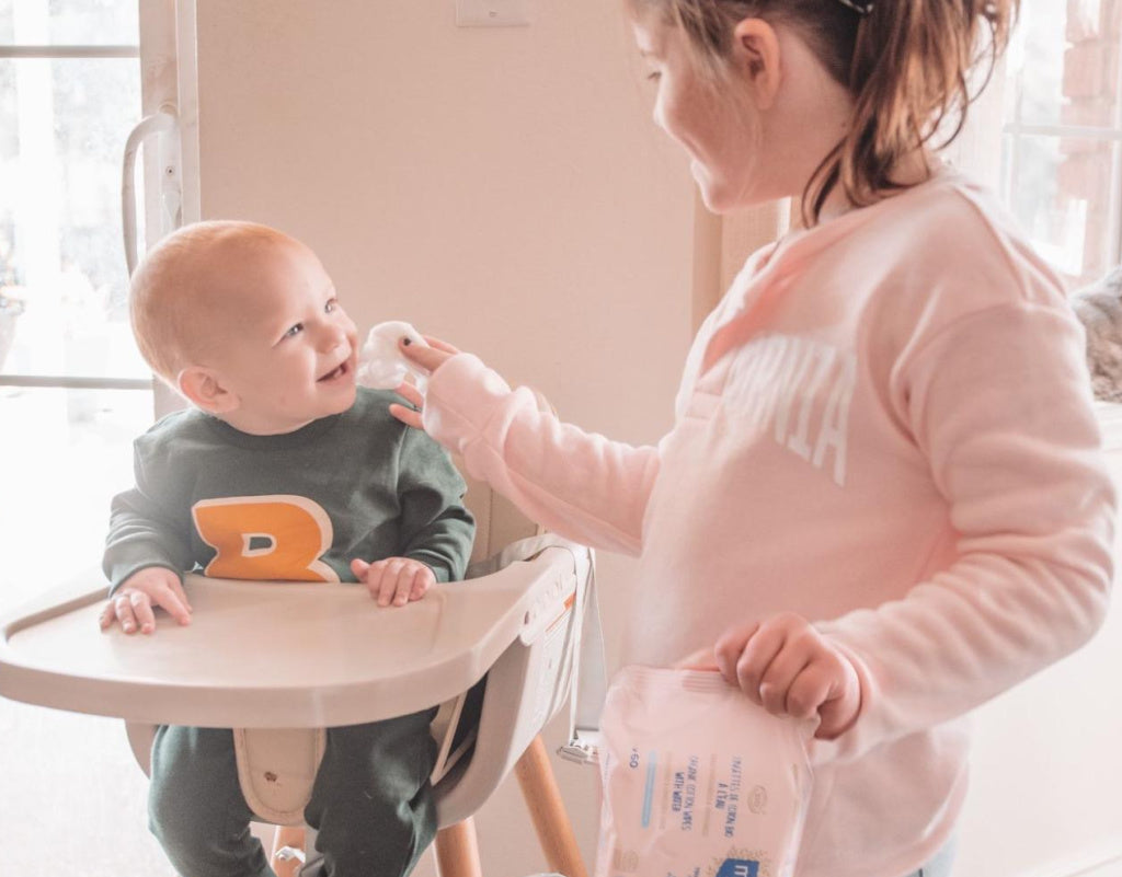 Sibling cleaning up younger siblings face after feeding