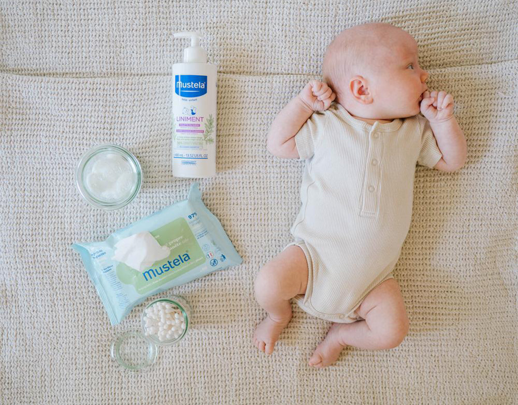 baby laying next to mustela baby products