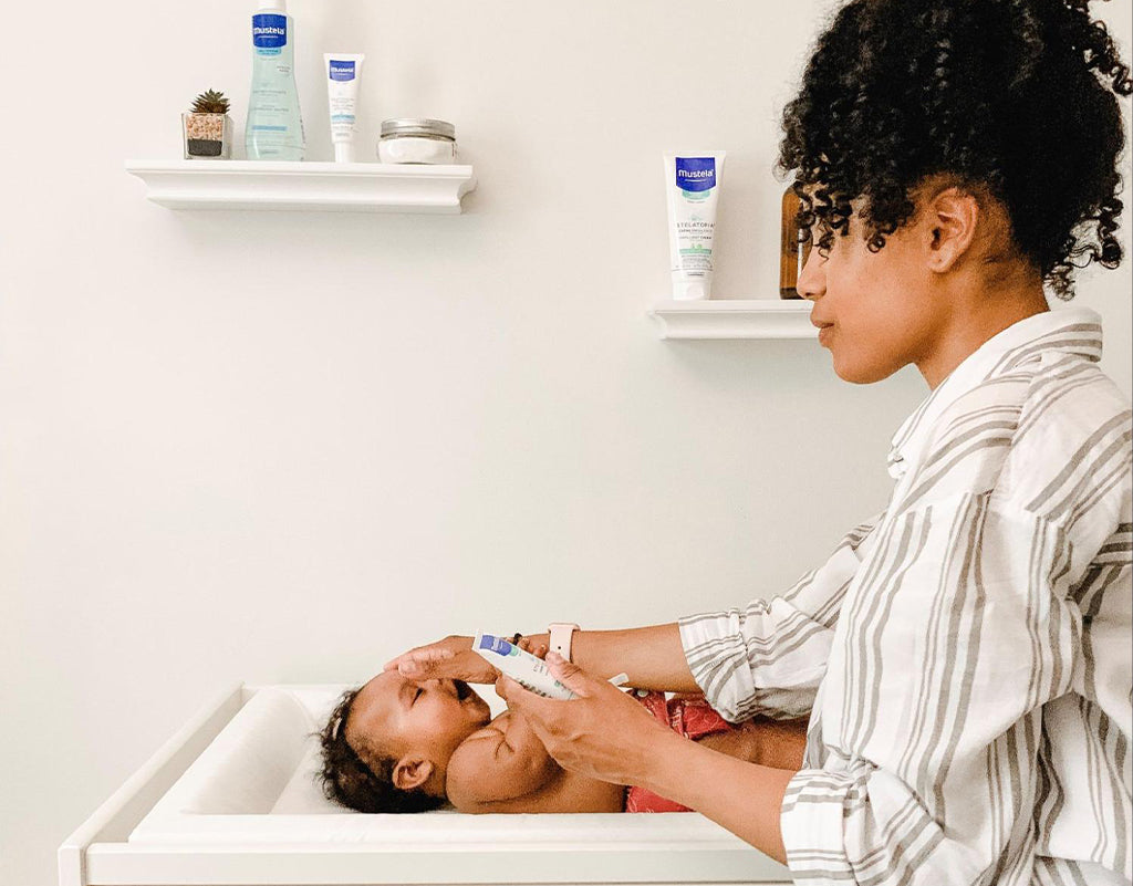 Mom applying diaper rash cream to baby