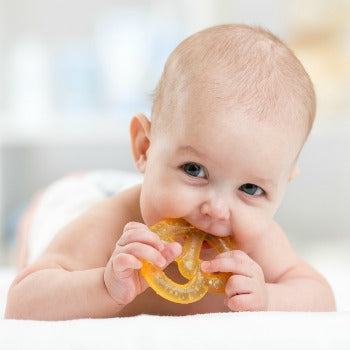 happy baby enjoying tummy time with an orange teether