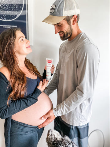 Pregnant mom with partner whose helping with applying stretch marks cream