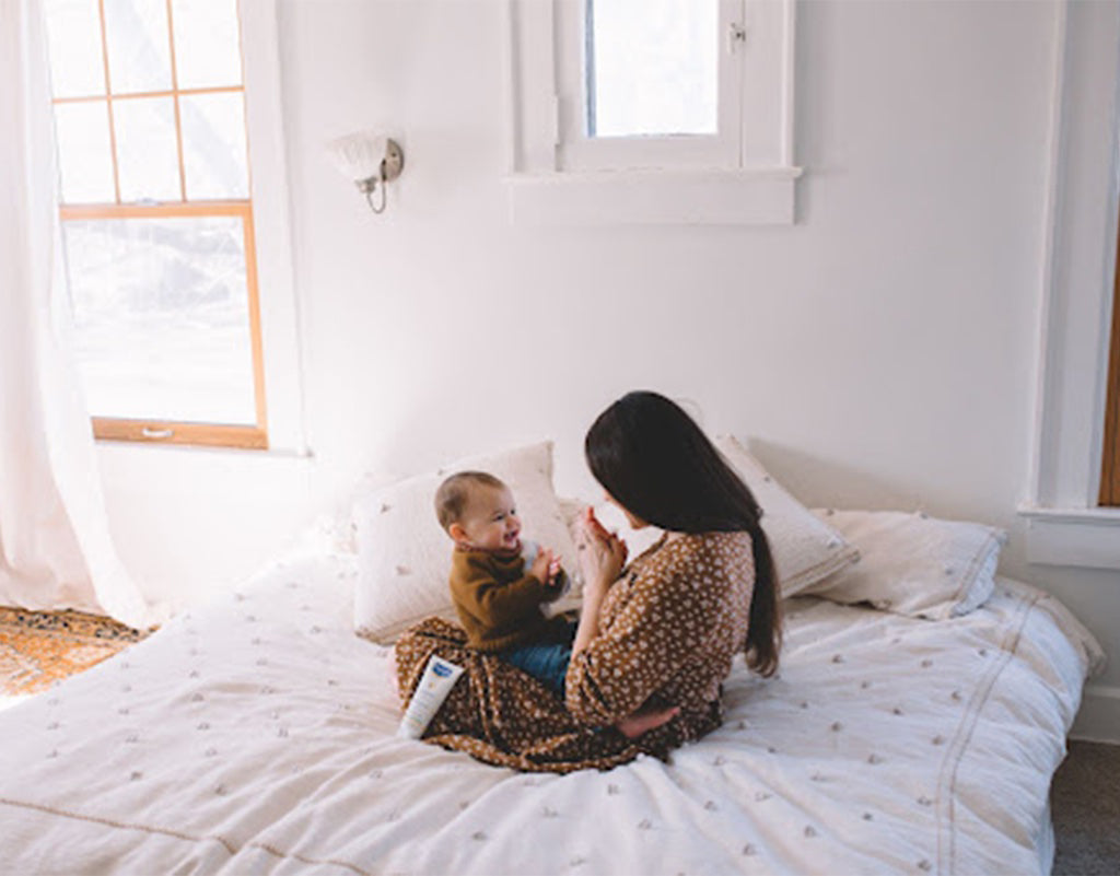 Mom holding baby on bed