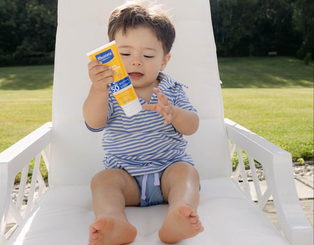 baby boy holding sunscreen 
