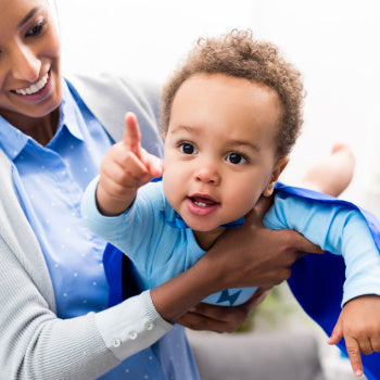 Mom playing superman with baby