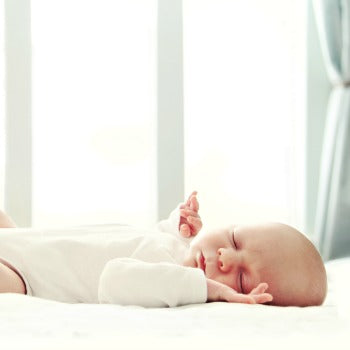 Baby laying on bed on back