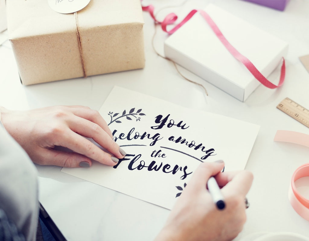 Person writing a card for baby girl gift