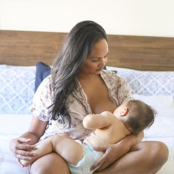 Mom breastfeeding baby on bed