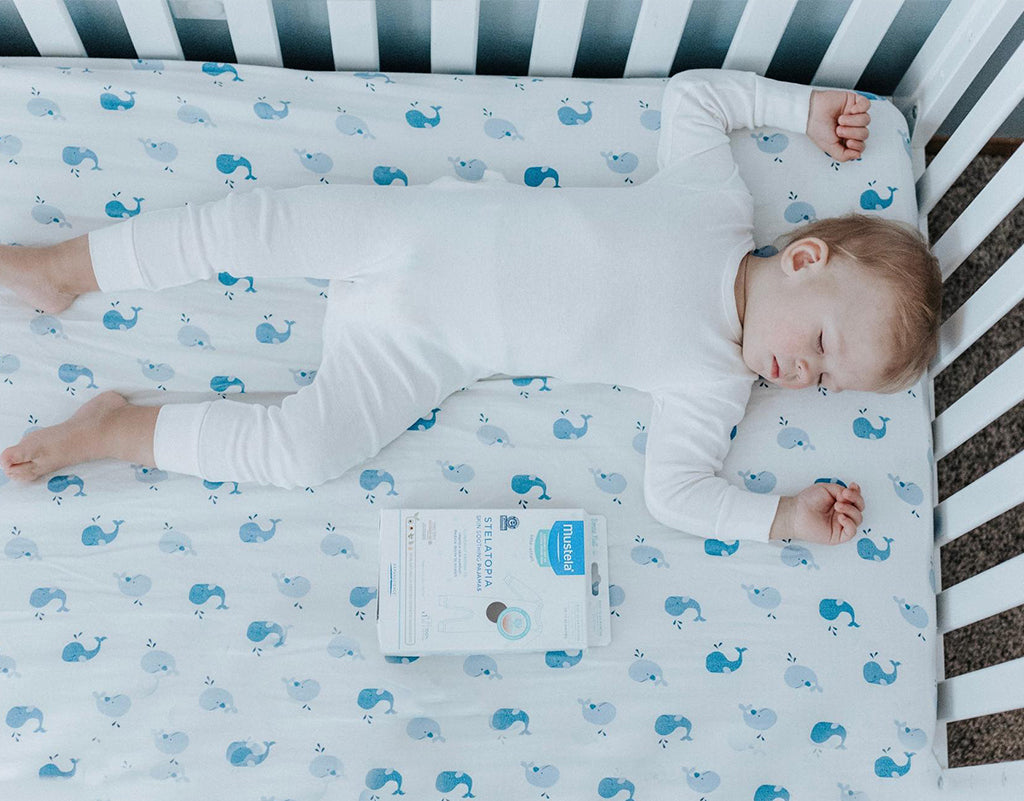 Baby sleeping in a crib sleeping in Mustela Stelatopia Skin Soothing Pajamas