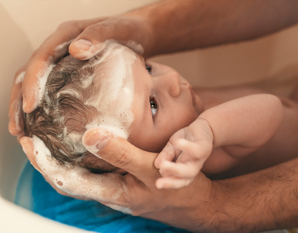 Parents washing baby's hair during baby's first bath