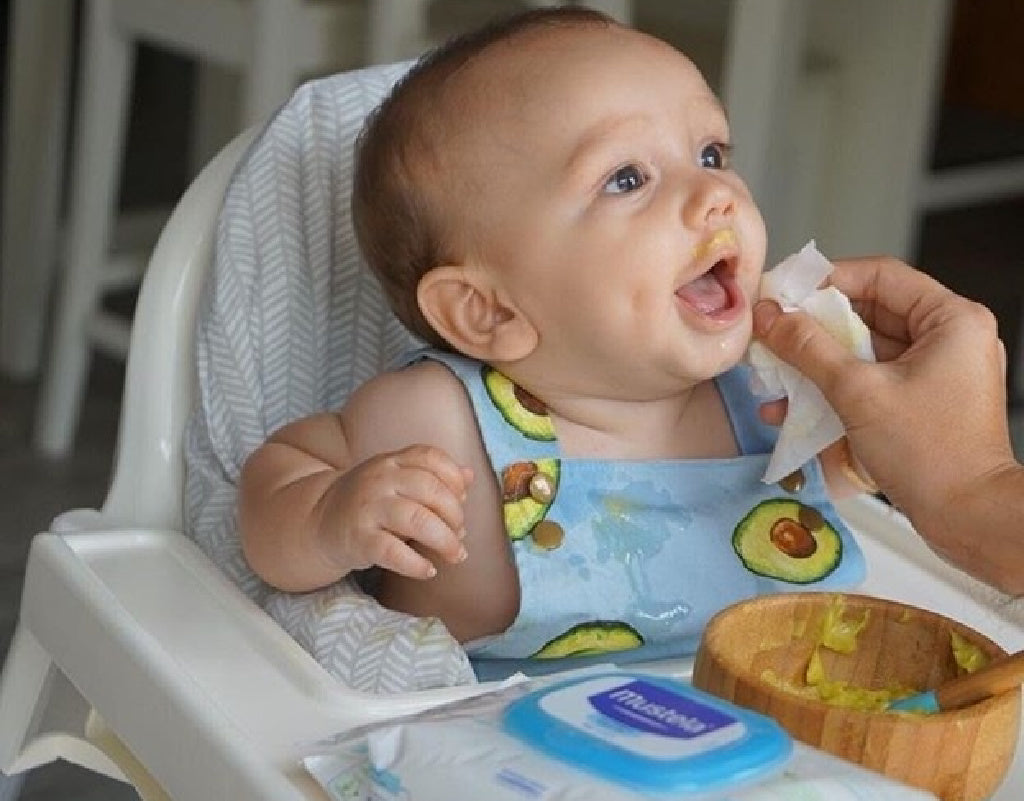 Parent wiping baby's face while feeding and ensuring baby safety