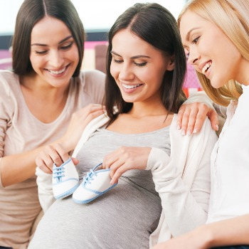 Women opening baby shower gifts with friends