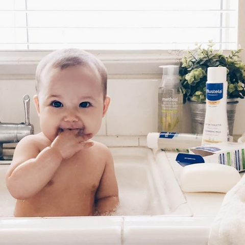 baby in bath with Mustela products