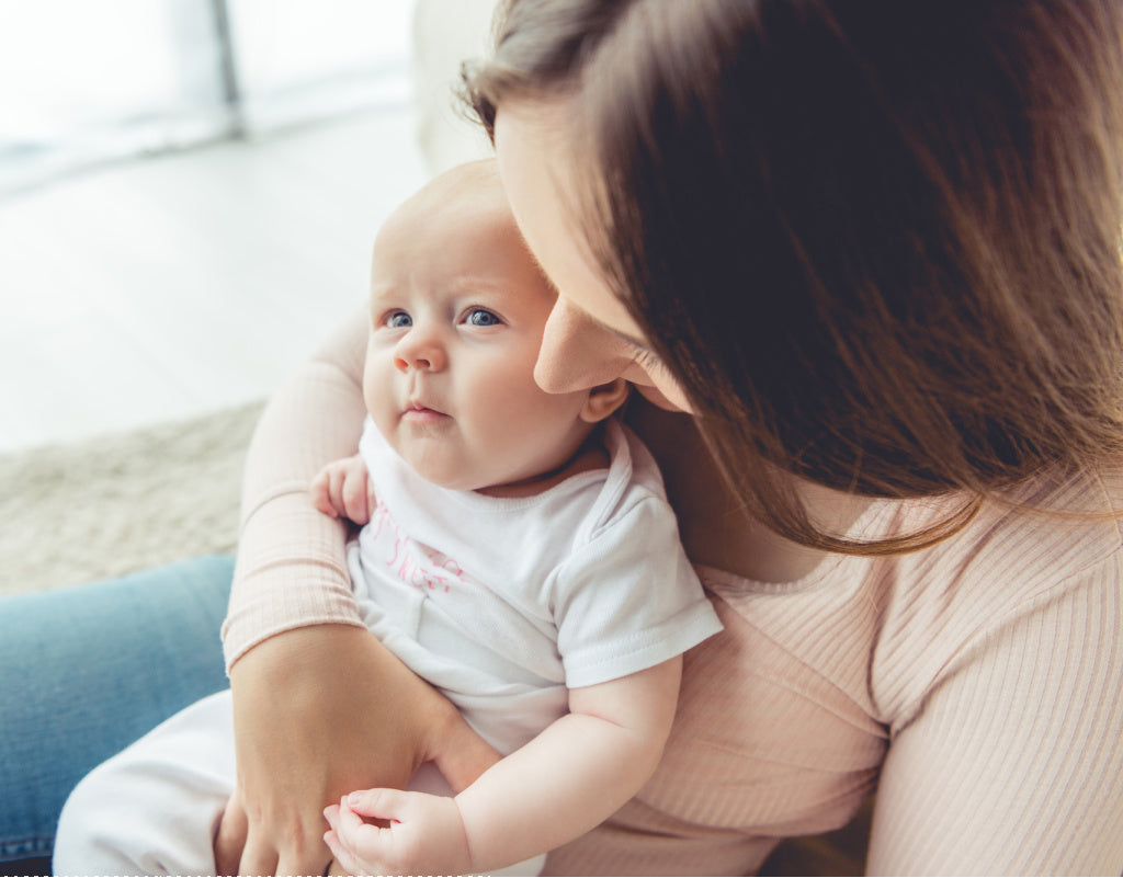 Mom sitting down trying to burp baby