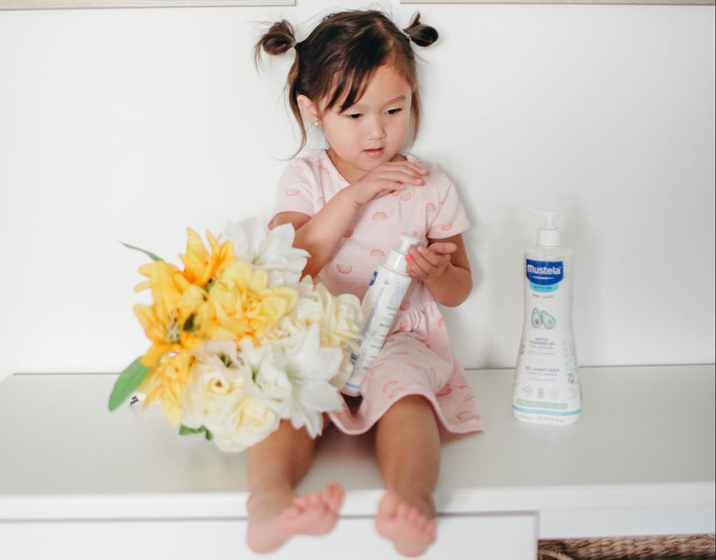 Young girl taking advantage of benefits of jojoba oil by using Mustela body lotion
