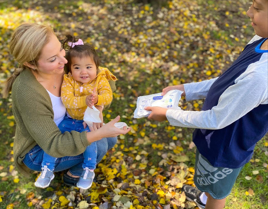 Young kid handing mom biodegradable baby wipes for baby