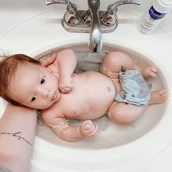 Mom bathing a baby in sink