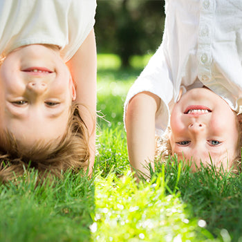 Two kids doing headstands on the grass