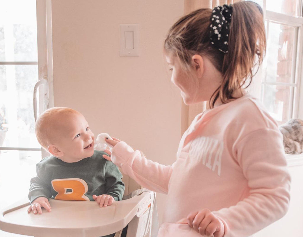 Sister cleaning siblings face with cloth baby wipes