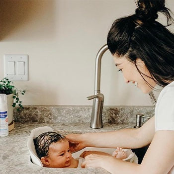 Mom giving baby a bath in the sink