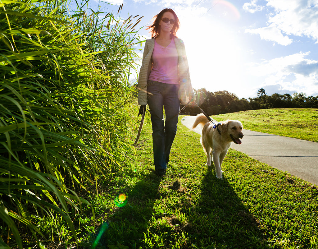 Woman walking dog while being protected by daily sunscreen