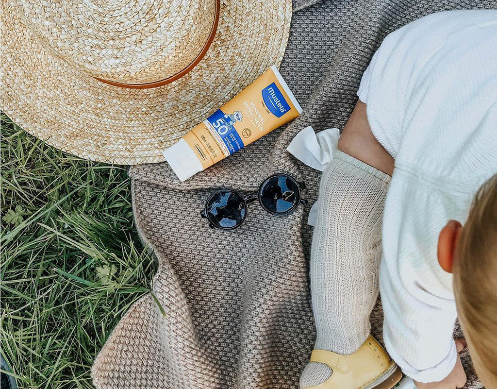 Mustela daily sunscreen next to child on blanket