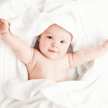 happy baby lying on towels with outstretched arms 