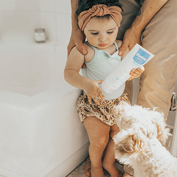 father and baby standing near bathtub with puppy 