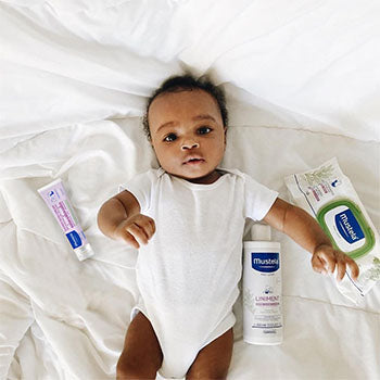baby surrounded by Mustela's Diaper Change Essentials
