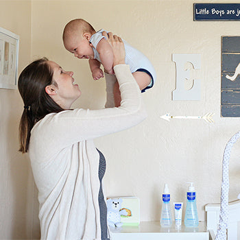 mother holding baby above her head as baby giggles