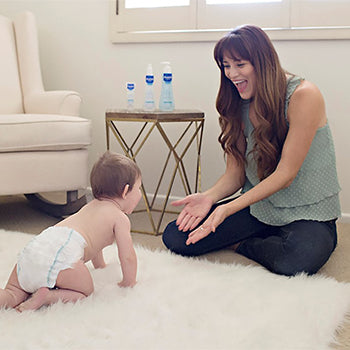 baby crawling towards mother on white rug