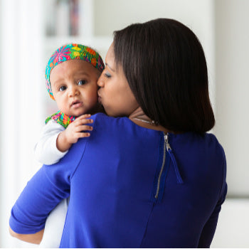 mom holding baby and kissing her cheek