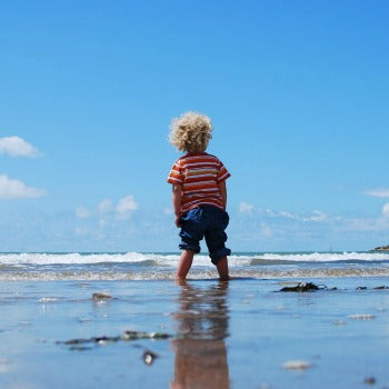 child standing in shallow beach water