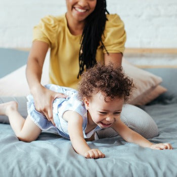 mother and baby playing on bed