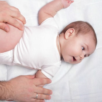 baby lying on his back as parent massages arms and legs
