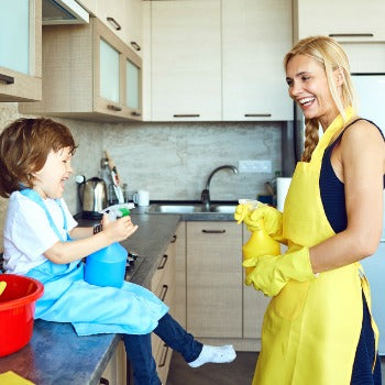 mother and young boy playing with squirt bottles in a kitchen 