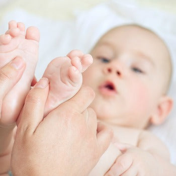 mother holding happy baby's feet while she lies on her back