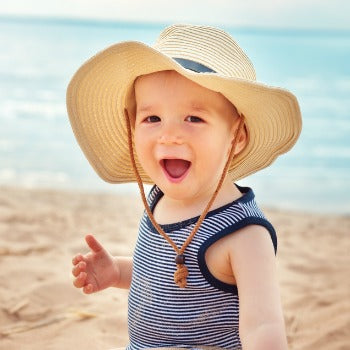 happy baby with sun hat at the beach