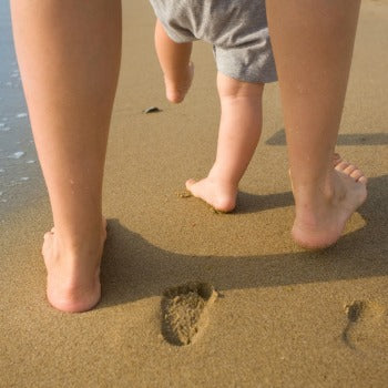 mother and baby walking in the sand