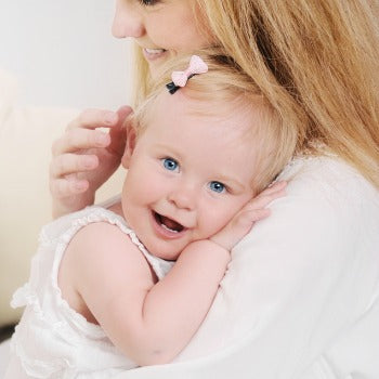 side view of mother holding smiling baby girl closely