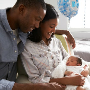 mother and father holding and smiling down at their newborn baby