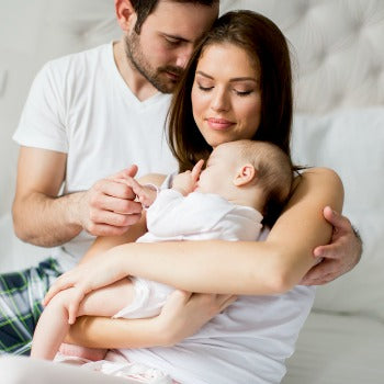 father holding newborn's hand while mother holds her