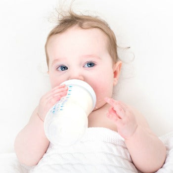 baby drinking from a bottle during newborn feeding schedule time