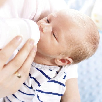 baby drinking from bottle during newborn feeding schedule